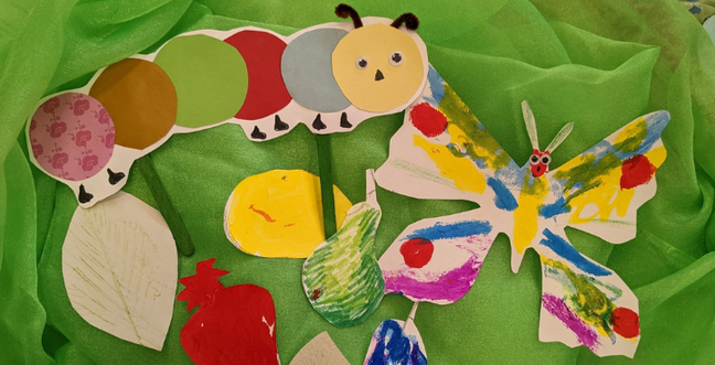A paper caterpillar and butterfly in multi-coloured paper