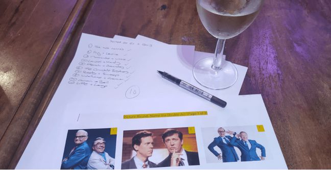 Quiz sheets on a table with a wine glass next to the pen and paper
