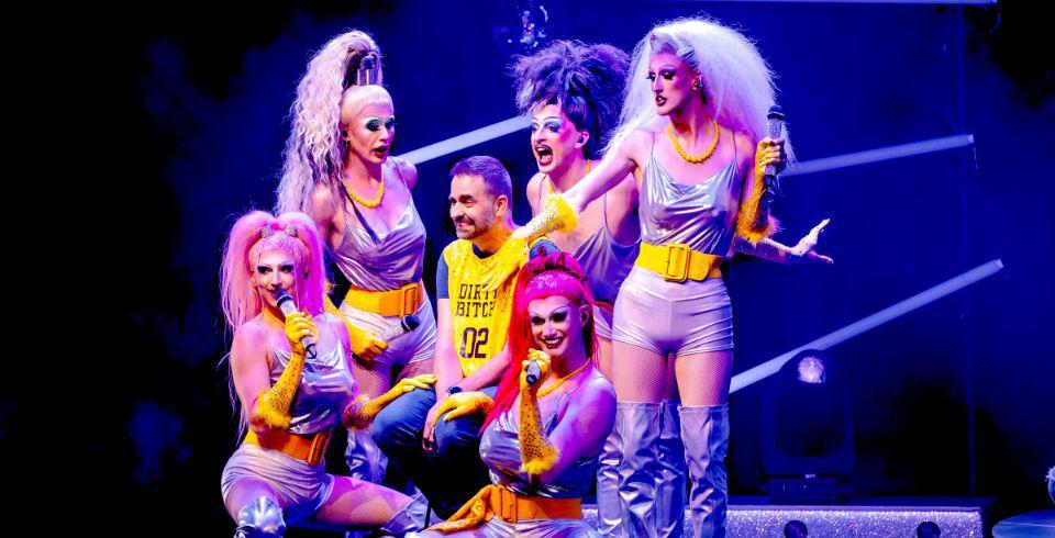 A group of performers on stage in yellow and silver outfits