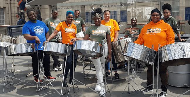 A group of people by steel pan drums outside