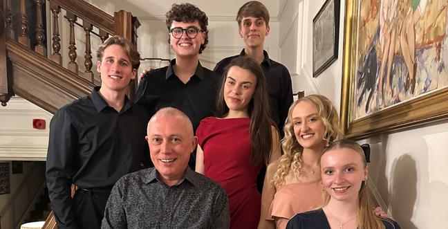 A group of people stand on a wooden stair case smiling together