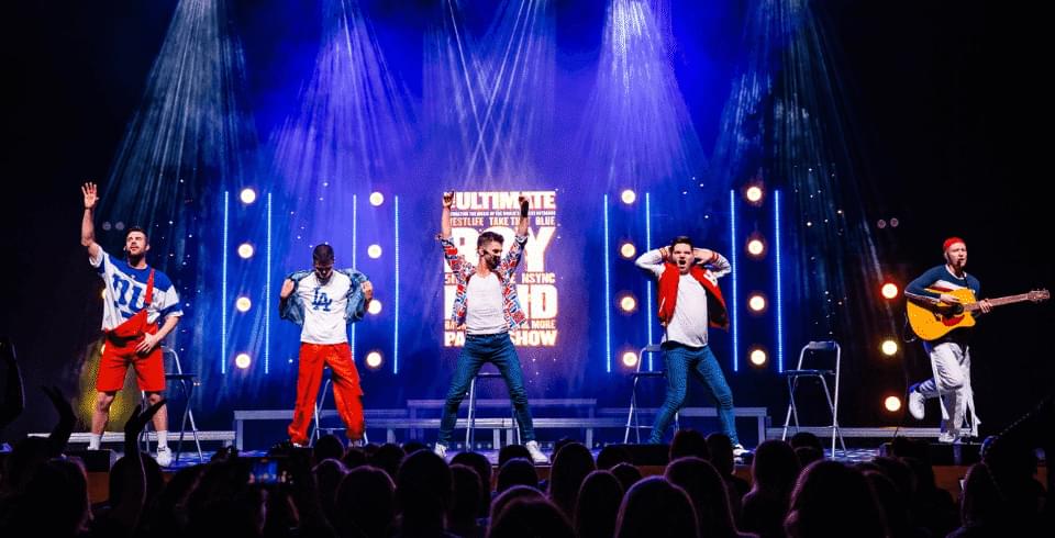 a group of men on a blue-lit stage wearing red and blue outfits