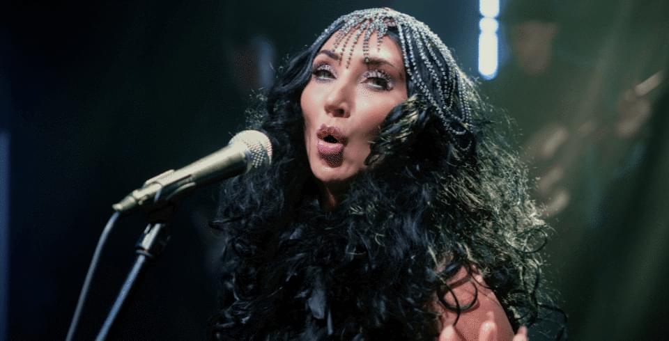 A woman in a sparkly headdress singing into a microphone