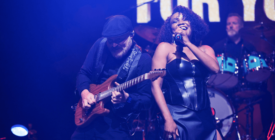 A woman in a black dress sings on stage