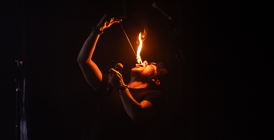 A man eating fire in a very dimly lit setting to beautifully show the flame