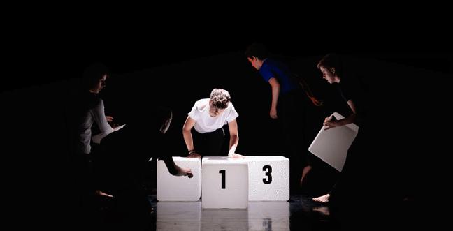 A group of performers climb over glowing number blocks