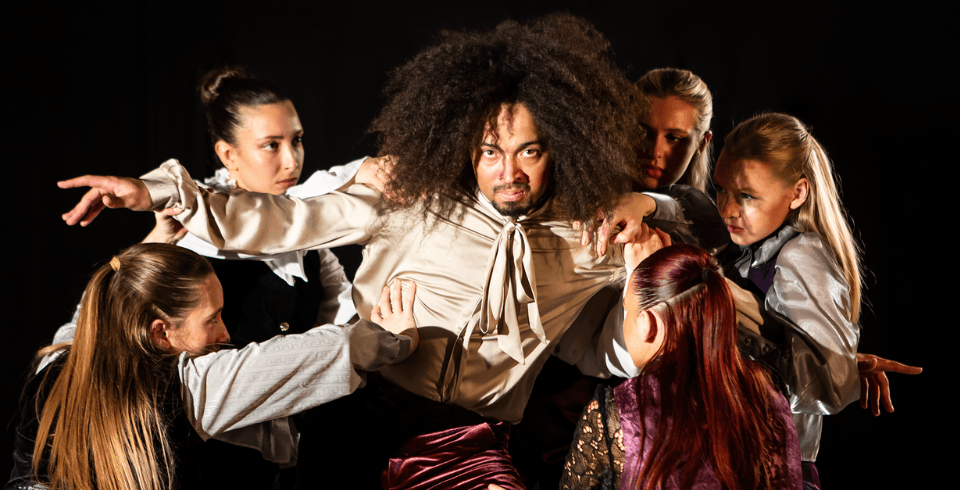 a man in a group of dancers wearing a white shirt and tie