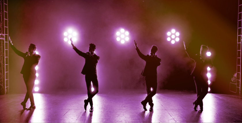 Four men on stage with pink lights behind them