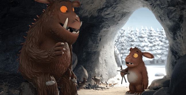 An animated Gruffalo leans with their child in a cave