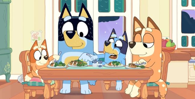Four cartoon dogs sit around a dinner table, two are blue and two are brown