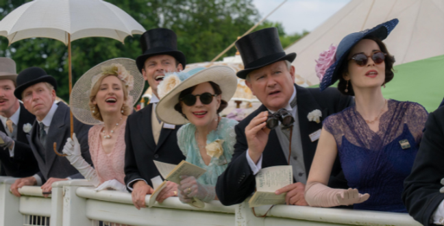 A group of elegantly dressed people standing by a railing. They are wearing vintage-style outfits with hats, gloves, and formal suits. The group looks excited and engaged, some holding binoculars and papers.