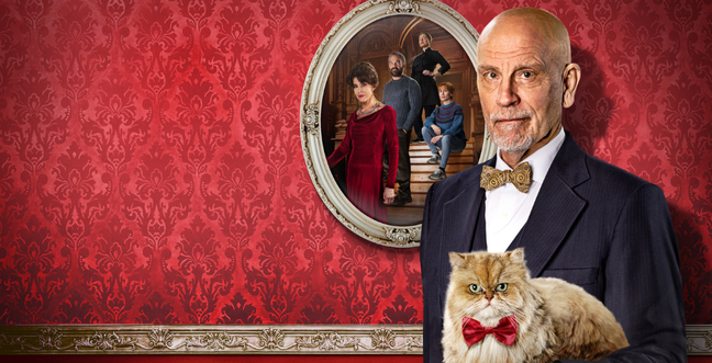 A man in a suit with a bow tie stands with a cat with a bow tie