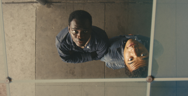 Two men look up into the camera which is suspended above them