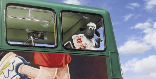 Shaun the Sheep leans out the top window of a double decker bus