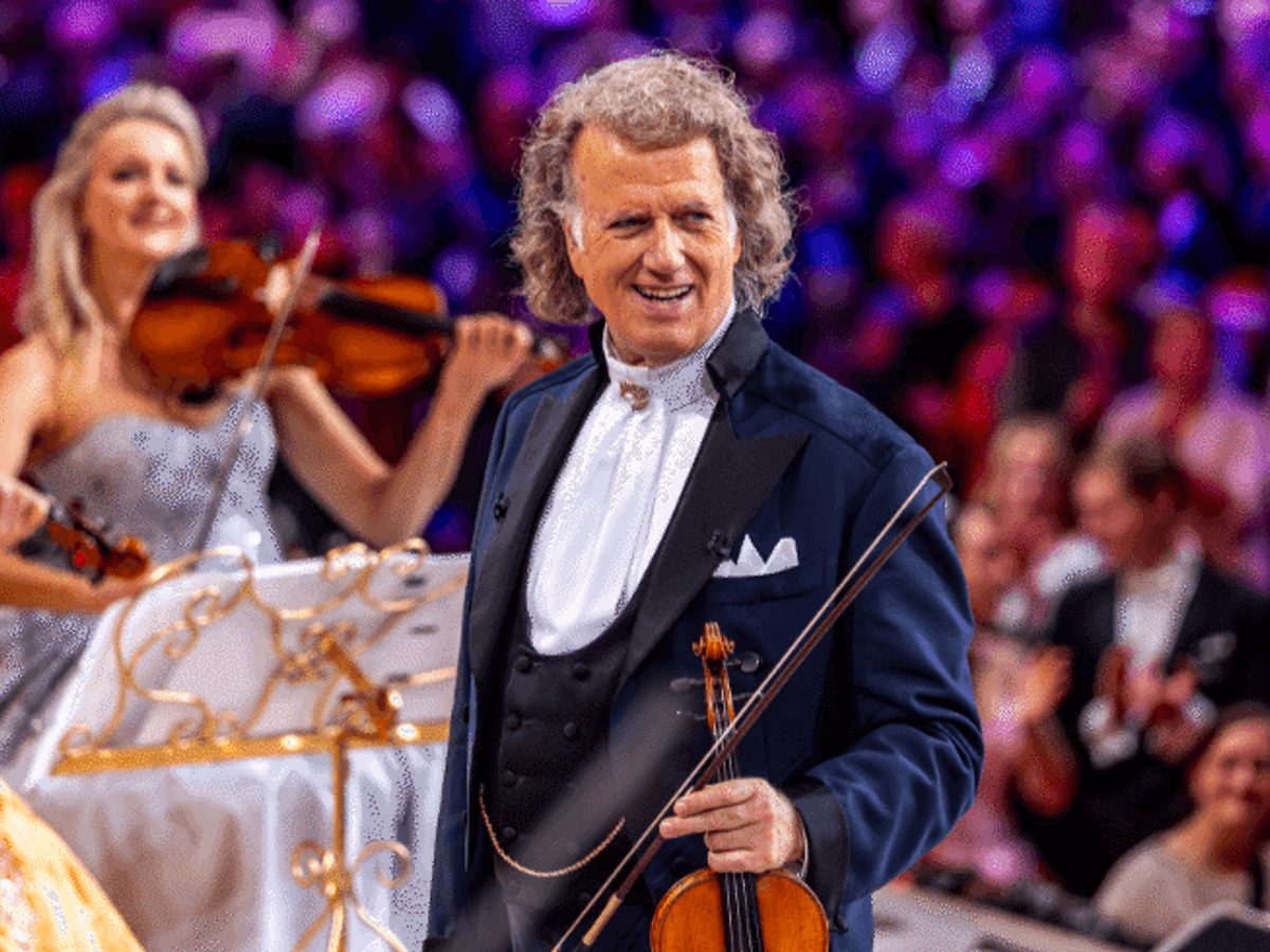 Andre Rieu holds a violin in front of a large crowd