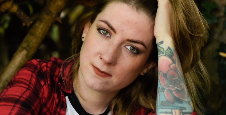 A women with a sleeve of tattoos pushes her brown hair back from her face