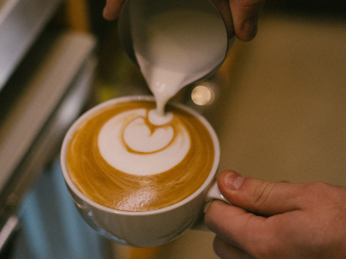 A coffee being poured into a coffee design