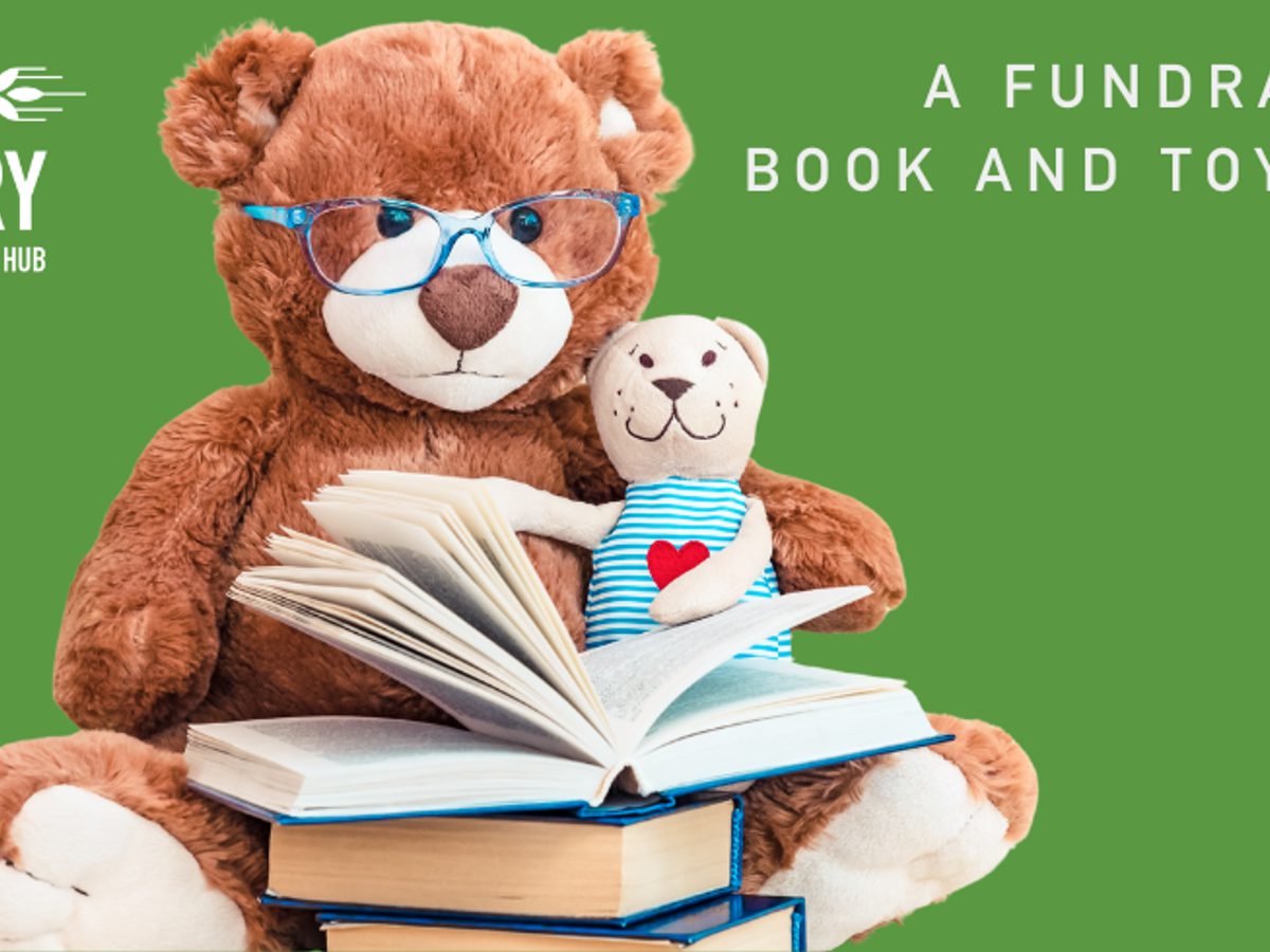 A teddy bear with glasses and books against a green backdrop