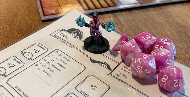 A sheet of paper with game play on it sits under a character figure and two D20 dice