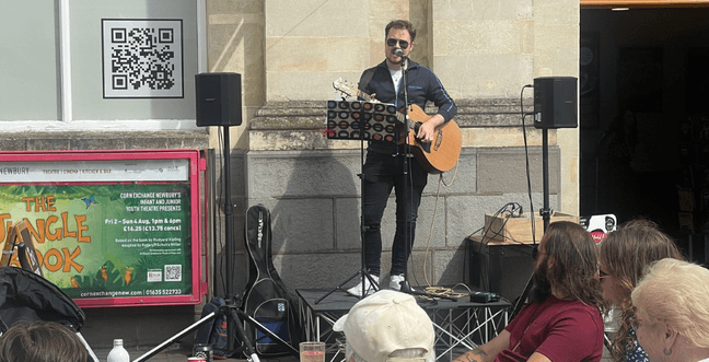 A man standing on a platform and playing guitar in front of a crowd.