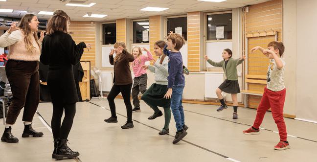 A group of children in a class jumping with the hands making the shape of a claw while they pretend to be tigers