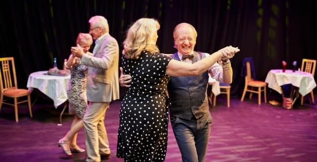 This is a photo of 4 adults dancing in 2 pairs. They are all smiling.