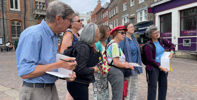 A group of people stand in a group with sketchbooks