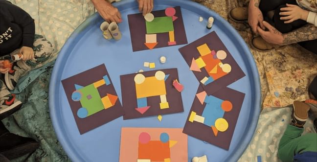 A group of kids around a circle table with cut-out artwork