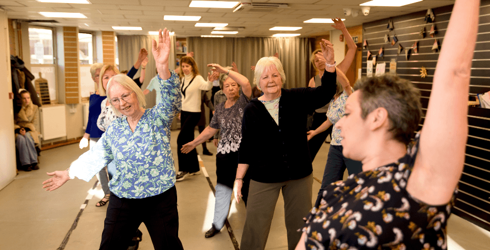 A class of women dancing in a group with one arm raised