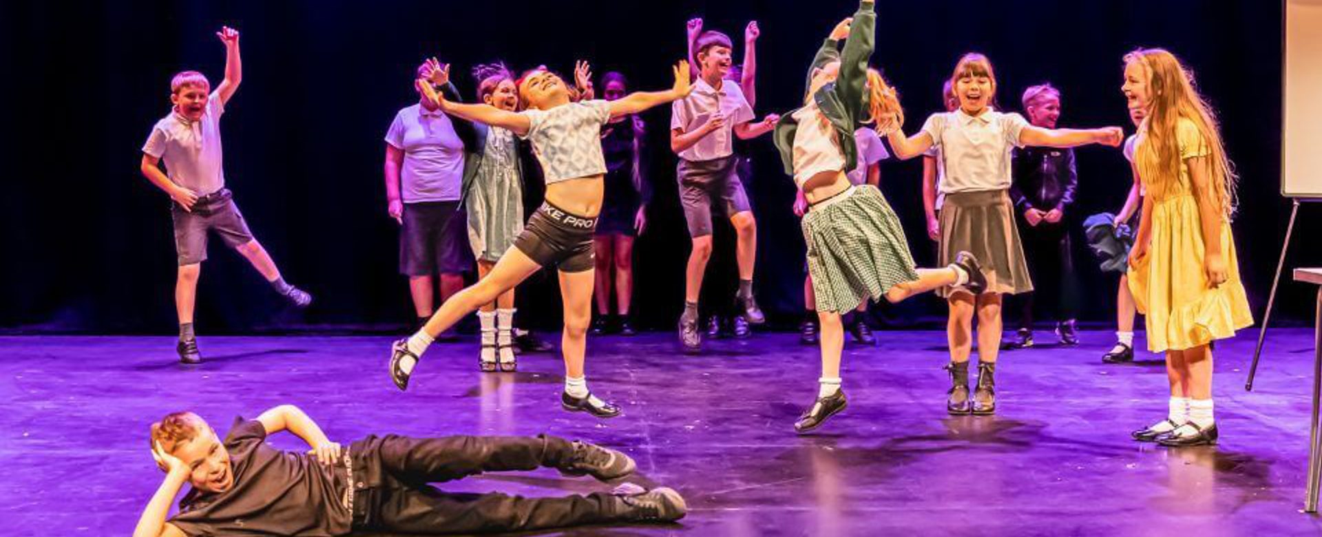 A group of young people jumping and smiling on stage