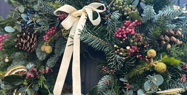 A Christmas wreath with a white bow on it