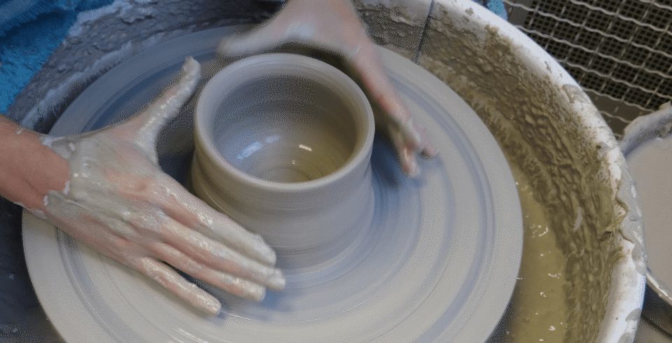 Hands on a pottery wheel, throwing a pot