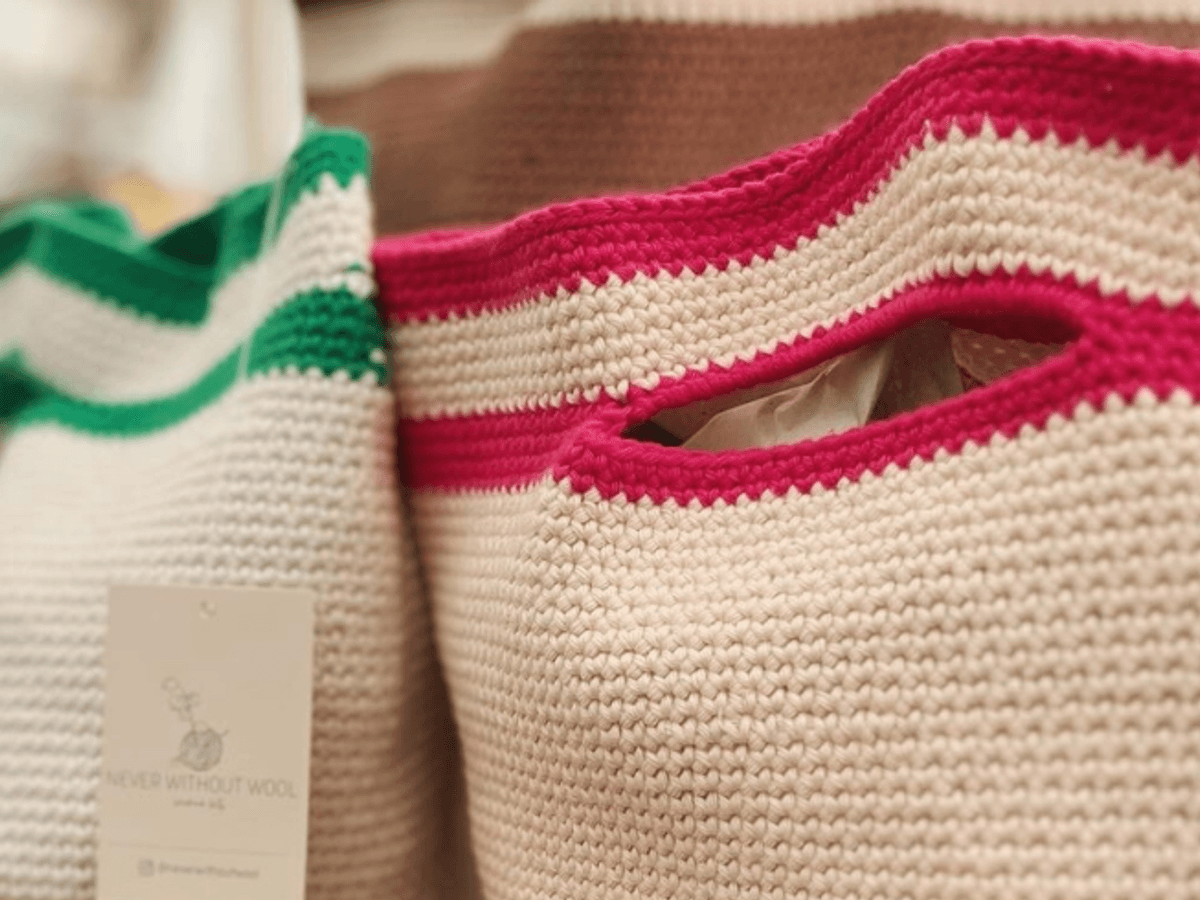 Three cream crochet bags sit next to each other, each has a signature accent colour green, brown and pink