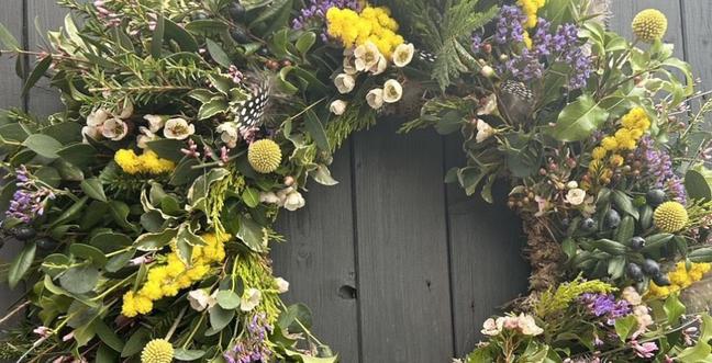 A green and yellow flower wreath on a grey door
