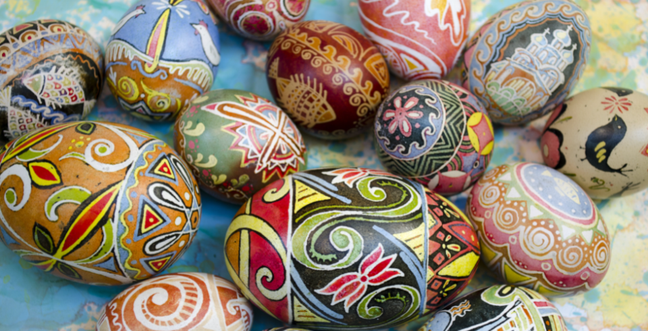 Multi-coloured painted eggs layed out on a colourful table
