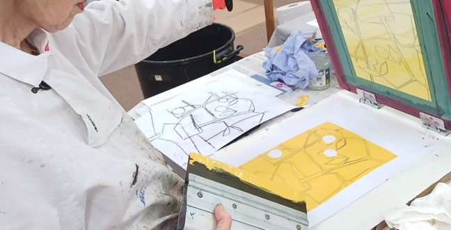 Using bright yellow ink a lady creates a silk screen print