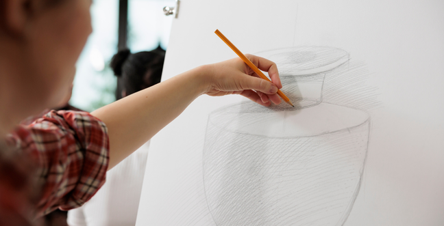 young person's hand using a pencil to draw on a canvas