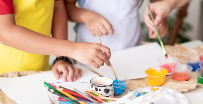 a children's workshop table full of painting materials and paper