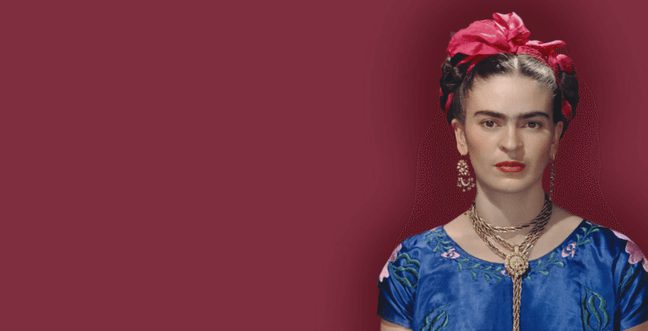 A woman wearing a blue dress and red headband standing against a dark red background.