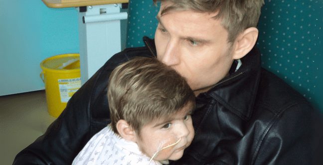 A man sat in a hospital chair with his child.