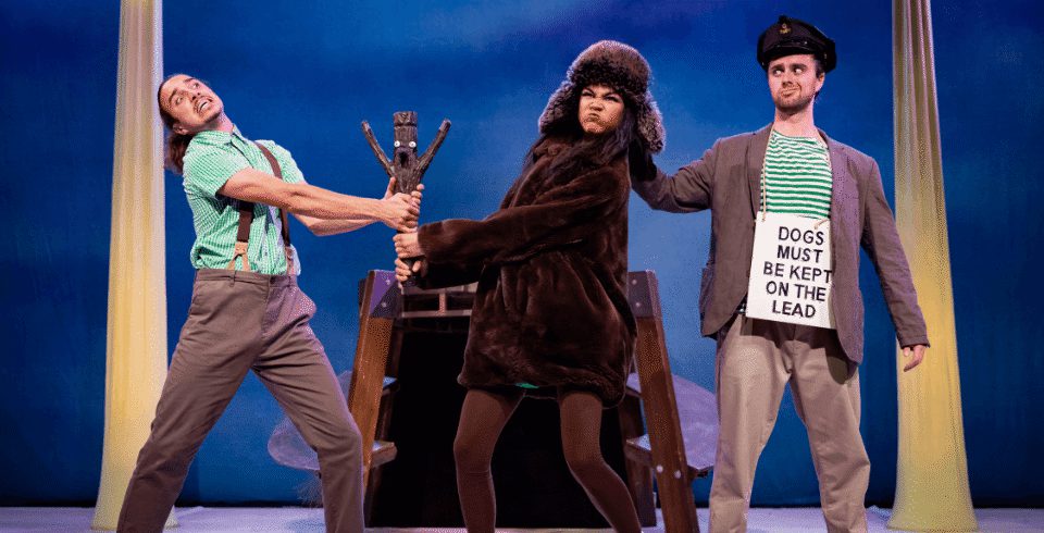 A man holding a wooden Stick Man while a woman dressed as a dog tries to take it from him.
