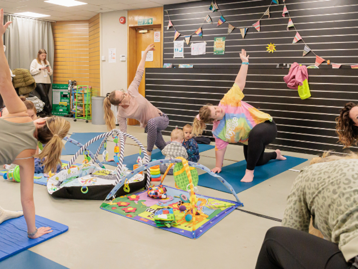 A group of women doing yoga with their babies in the middle of them all.
